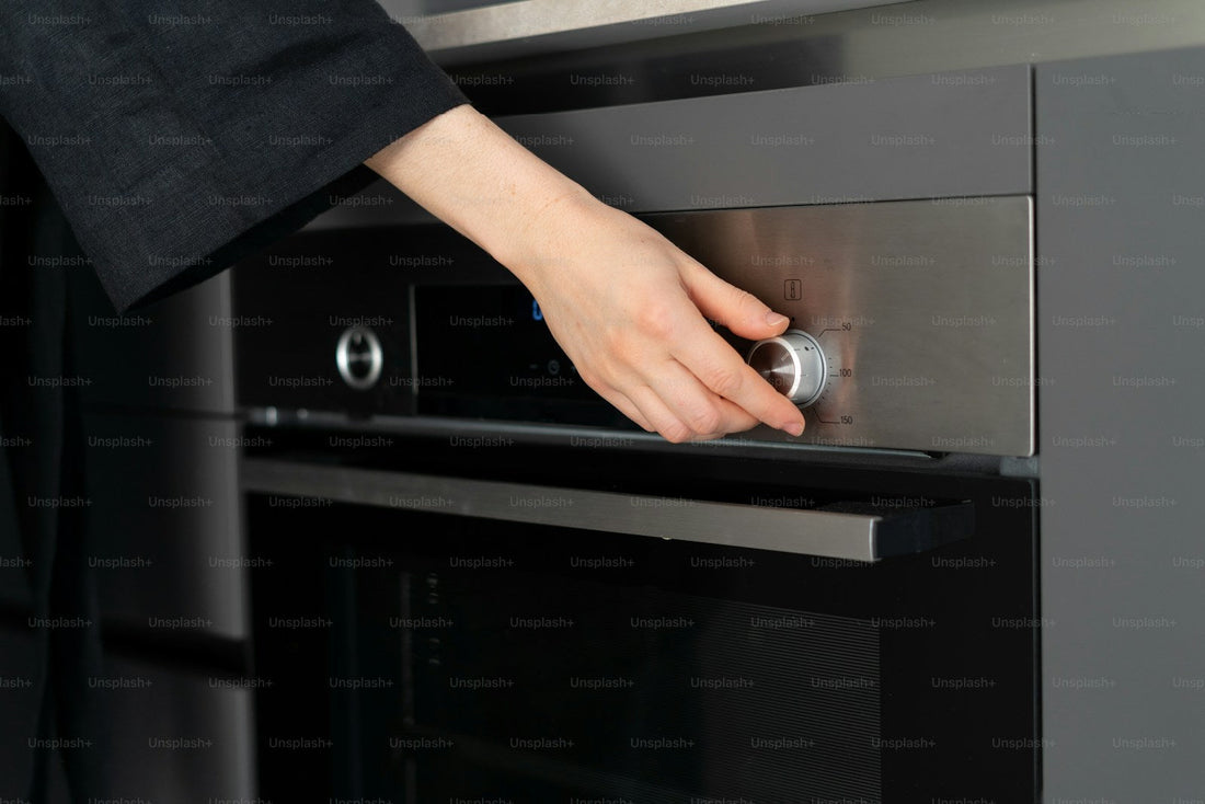 Person turning the control dial on a stainless steel oven
