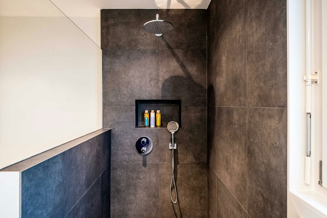 Stainless steel showerhead mounted against white bathroom tile