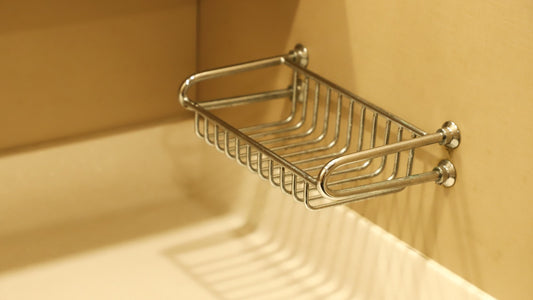 A stainless steel shower rack mounted on a white tiled wall