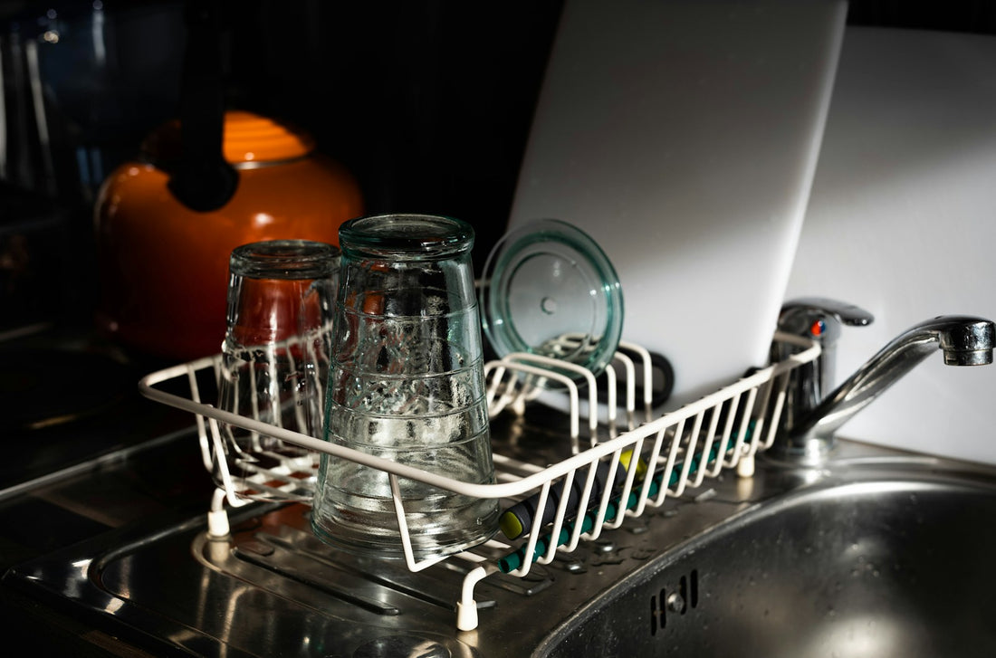 Clear glass mugs drying on a white metal dish rack