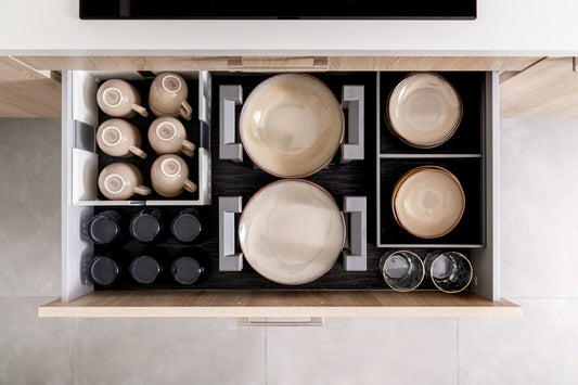 An organized drawer holding dishes, glasses, and cups