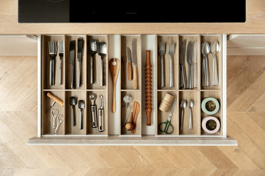 An organized kitchen drawer with separate compartments for utensils