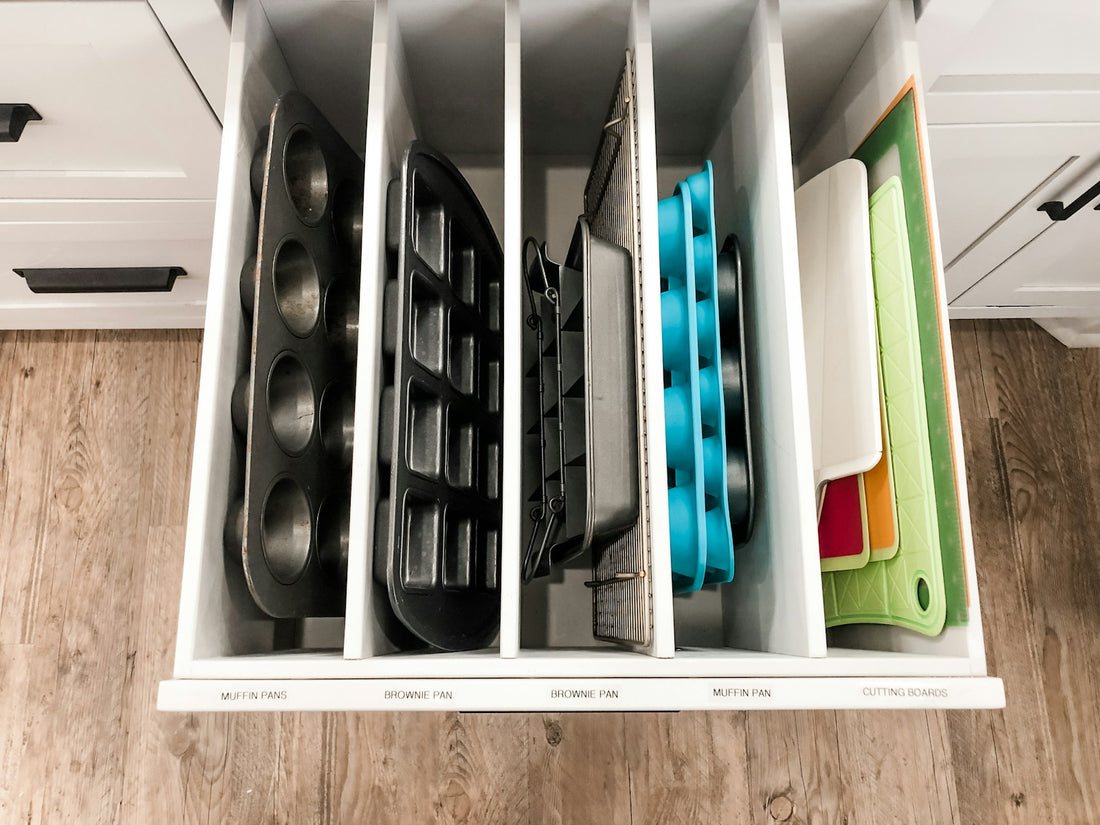 Baking pans and cutting boards stored vertically in an organized kitchen drawer