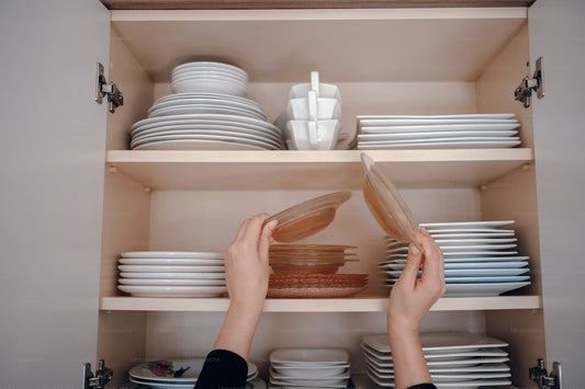 A person reaching for a plate in a neatly organized kitchen cabinet