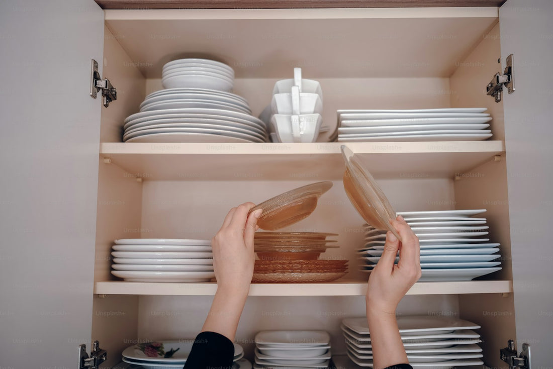 A person reaching for a plate on neatly organized cabinet shelves