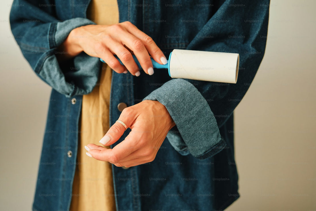 A lint roller being used carefully on the sleeve of a denim shirt